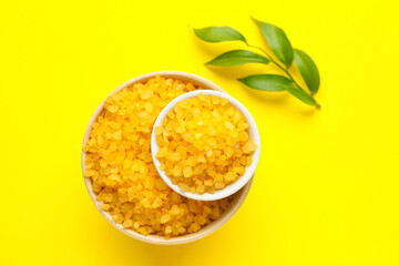 Bowls of orange sea salt on yellow background