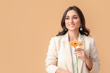 Woman with stylish jewelry holding gerbera flower on color background. International Women's Day