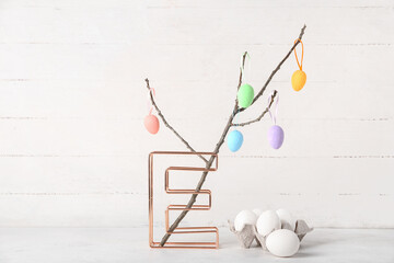 Tree branches, Easter eggs and letter E on white wooden background