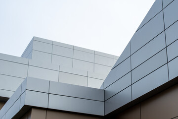 The exterior wall of a contemporary commercial style building with aluminum metal composite panels and glass windows. The futuristic building has engineered diagonal cladding steel frame panels.