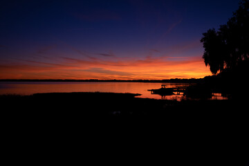 A sunset or sunrise over a calm blue ocean. The horizon is bright orange as the sun crescents the...