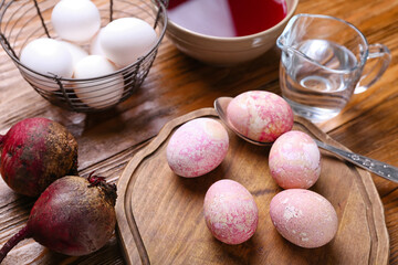 Easter eggs, beets and bowl with homemade natural dye on wooden table, closeup