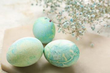 Obraz na płótnie Canvas Board with beautiful Easter eggs and gypsophila flowers, closeup