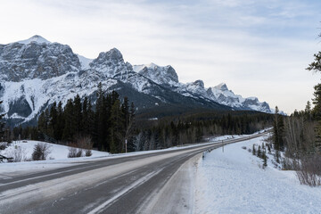 Fototapeta na wymiar Alberta Highway 742 Three Sisters Parkway in winter. Snowcapped Canadian Rockies mountain range. Canmore, Alberta, Canada.