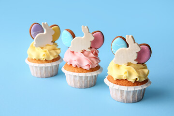 Tasty Easter cupcakes on blue background