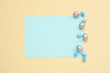 Composition with sheet of paper and Easter eggs on blue background