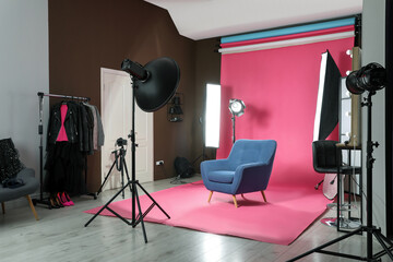 Stylish blue armchair in photo studio with professional equipment