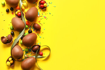 Composition with chocolate Easter eggs, different candies and sprinkles on yellow background