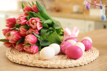 Easter eggs and bouquet of tulips on wooden counter