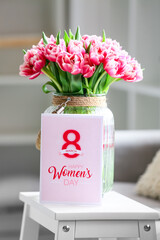 Bouquet of tulips and greeting card with text HAPPY WOMEN'S DAY on stepladder stool