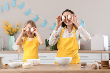 Little girl with her mother having fun while cooking Easter cake in kitchen
