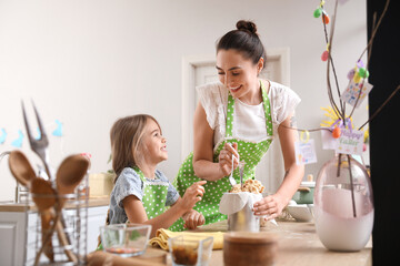 Little girl with her mother preparing Easter cake in kitchen