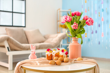 Fototapeta na wymiar Easter cakes, eggs and vase with beautiful tulips on table