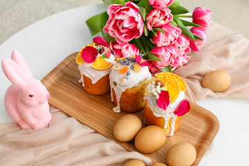 Tray with Easter cakes, eggs and tulips on table