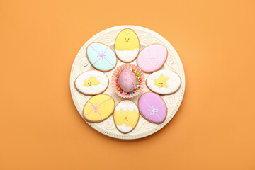 Plate with tasty Easter cookies and egg on color background