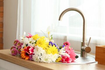 Bouquet of beautiful flowers in sink near window