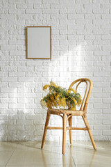 Mimosa flowers on chair near white brick wall in room. International Women's Day celebration