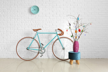 Tree branches with Easter decor and bicycle near white brick wall