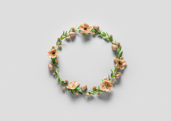 Beautiful wreath with Easter eggs and flowers on light background