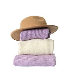 Stack of knitted sweaters and felt hat on white background