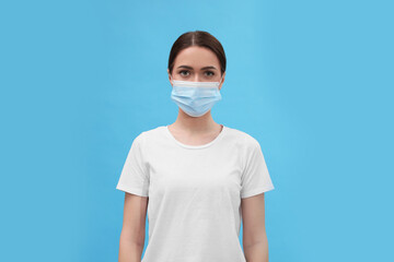 Portrait of woman in medical mask on light blue background
