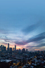 New York City skyline lights at dusk with empty blue sky above the buildings of Lower Manhattan
