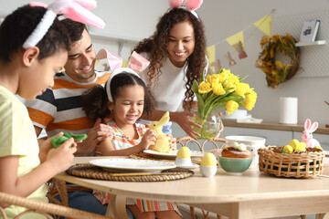 Happy family at dining table in kitchen on Easter day