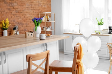 Vase with flowers, cup and cube calendar with date 8 MARCH on kitchen counter. International Women's Day celebration