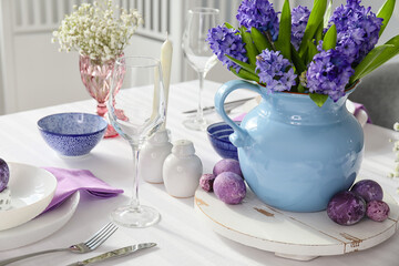 Beautiful flowers, Easter eggs and stylish dinnerware on table