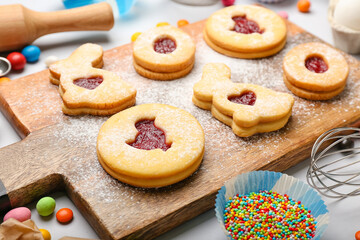 Board with delicious Easter cookies on light background