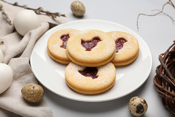 Plate with delicious Easter cookies on light background