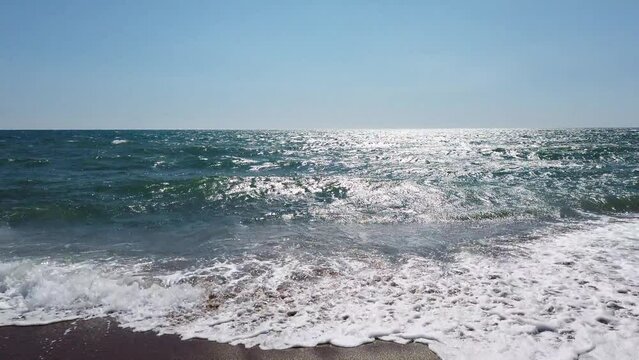 Sonniger Sommertag am Meer. Sch&auml;umende Wellen, klarer blauer Himmel und goldener Sand. Glitzernde Wellen, smaragdgr&uuml;ne, T&uuml;rkis krachende Wellen. Meditieren in Italien, Sabaudia, Tyrrhenisches Meer.