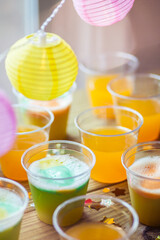 Clear plastic cups with colorful juice cocktail punch mixed drink on table at party