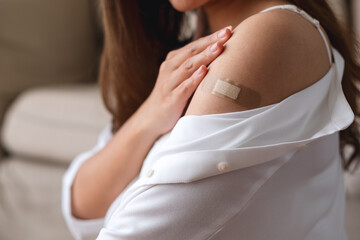 Closeup image of a young woman with adhesive bandage, medical plaster, band aid on her shoulder for...