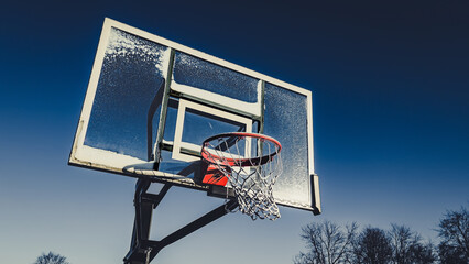 Snow splattered basketball hoop in winter