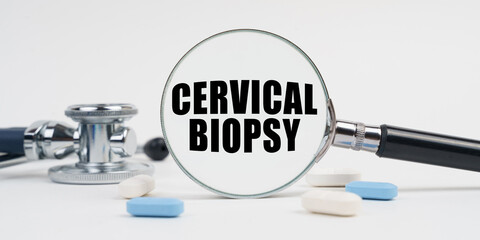 On a white surface lie pills, a stethoscope and a magnifying glass with the inscription - Cervical Biopsy