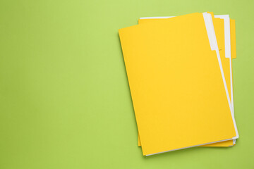 Yellow files with documents on light green background, top view. Space for text
