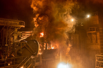 Electric arc furnace during operation. Lots of smoke and fire