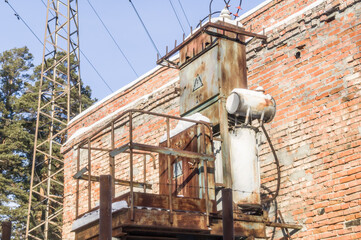 Old high-voltage transformer of city power supply. Rusty equipment of the power plant. Selective...