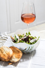 Simple healthy salad in modern bowl on kitchen counter with wine and bread