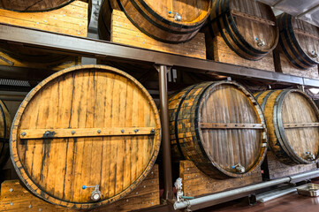 Racks with wooden casks of upscale alcohol drinks in cellar