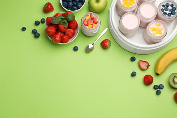 Yogurt maker with jars and different fruits on light green background, flat lay. Space for text
