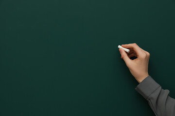 Woman with white chalk near green board, closeup. Space for text