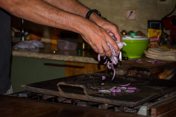 Fototapeta na wymiar man's hands putting chopped onion on a kitchen griddle, background food