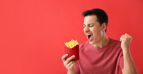 Emotional young man with french fries on red background