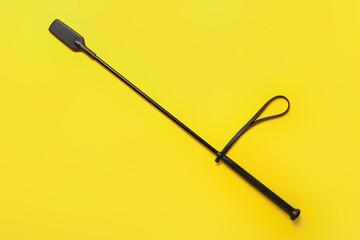Horse riding crop on yellow background