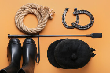 Horse riding helmet, boots and crop with rope and horseshoes on color background
