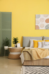 Stylish interior of modern bedroom with yellow wall