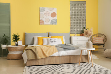 Stylish interior of modern bedroom with yellow wall