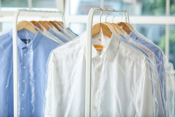 Racks with clean shirts in plastic bags after dry-cleaning